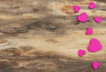 Eight pink hearts of different sizes on a natural wooden background. Background with copy space. Horizontal orientation. Valentine's day or wedding card