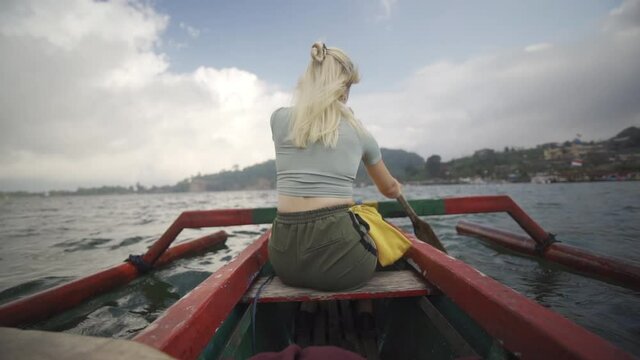 Woman Rowing Outrigger With Oar In Bali