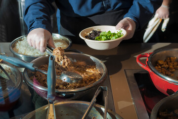 Close-up of hands serving latin food in dishes on a counter