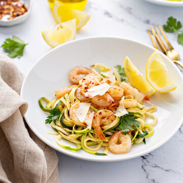 Shrimp And Zucchini Noodles Or Zoodles Pasta With Parmesan And Chili Flakes With Lemon In White Bowls