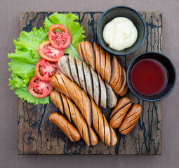 Fried sausages recipe with fresh tomato and sauces ketchup ready to be served, international food style concept