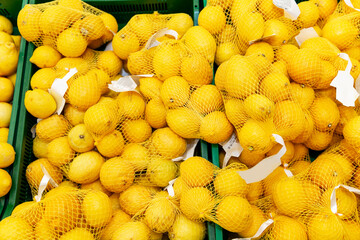 Fresh lemons in factory nets on the counter in the store.