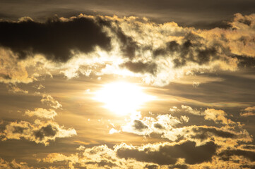 Closeup of the sun setting behind some clouds