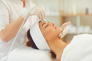 Obraz na płótnie Canvas Woman getting facial skin ultrasound cavitation and anti-aging cosmetics from cosmetologist