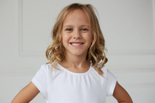 Close up image of an adorable smiling little girl showing her teeth chewing a gum, white background. Horizontal view.