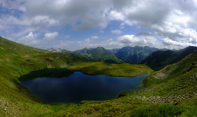 Fototapeta na wymiar wonderful deep blue mountain lake in a green valley in the mountains panorama