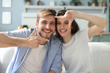 Obraz premium Romantic beautiful smiling couple making selfie for fun, at home sitting on the sofa.