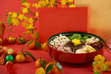 Round tin box with dried fruits, nuts, roasted melon seeds, crackers with best wishes inscription and tangerines for Lunar New Year celebration