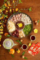 Round tin box with sweet dried fruits, nuts and fried melon seeds, tea cups and cards with best wishes inscription for Lunar New Year celebration