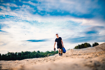 Man carries snowboard equipment for descending on sand in desert. Vacation concept in Arab Emirates and Africa