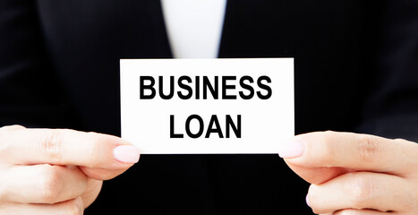 The businessman holds a business card with the text Business Loan with two hands.