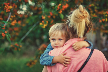 Portrait of a boy in the arms of his mother on a walk . Family values . - 408027811