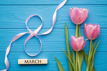 Happy women's day concept. Flatlay photo of bunch of tulips ribbon in shape of number eight and text showing word march on bright color blue desk backdrop