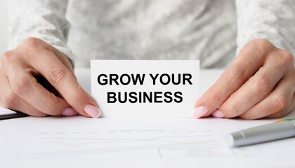 The girl holds a card with the text GROW YOUR BUSINESS, next to the pen.