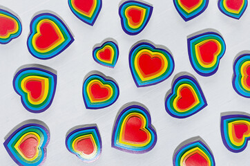 Fun colorful lgbt valentine's day abstract background - rainbow valentines hearts on white wood board, pattern, top view.