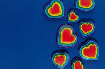 Lgbt background - decorative border of rainbow hearts on dark blue backdrop, copy space.