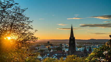 Germany, Freiburg im Breisgau, Magical orange sunset sky and sunrays behind skyline of the...