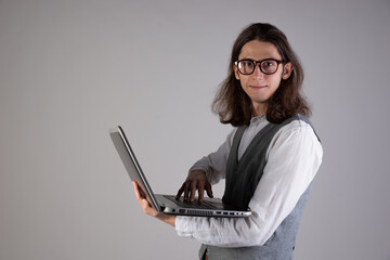 Programming and writing code, developing software products. Geek guy, with long hair and glasses, holding a laptop, gray background