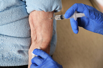 A 90-year-old woman is given the covid-19 vaccine by a doctor. Vaccination of the elderly. Senior...