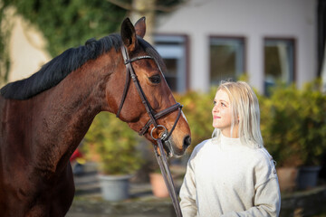 Young woman stands across from her horse and they both look into each other's eyes..
