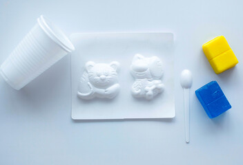 Children's hands making soap mix and pour liquid into molds on white table. Step-by-step...