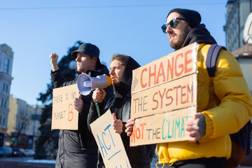 A group of people with banners and a megaphone in hand are protesting in the city square for svae...