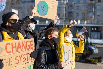 Obraz na płótnie Canvas A group of people with banners and a megaphone in hand are protesting in the city square for svae planet clean world act now