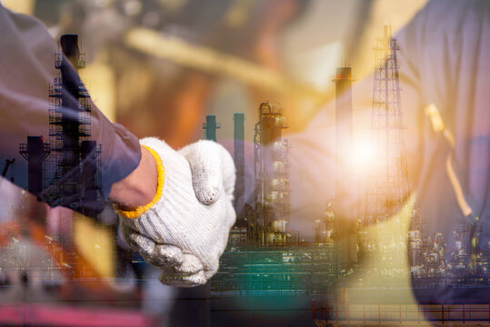 Double exposure of engineer mechanic man team get handshake together after checking with petrochemical refinery plant at night, teamwork concept	