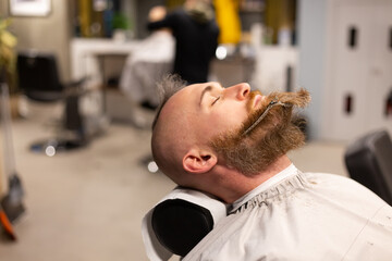 Obraz premium European brutal man with a beard cut in a barbershop