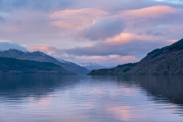 Majestic landscape image across Loch Lomond looking towards snow capped Ben Lui mountain peak in Scottish Highlands