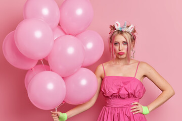 Unhappy woman upset something went wrong on party wears pink festive dress has trendy hairstyle...