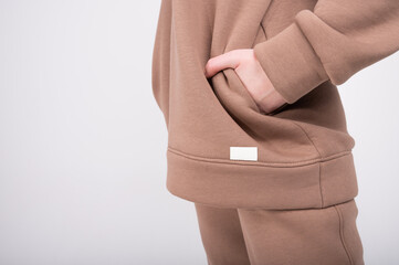 Side view of young woman in taupe hoodie with copy space isolated on white. Beige female sweatshirt with blank label. Fashion clothes, streetstyle concept.