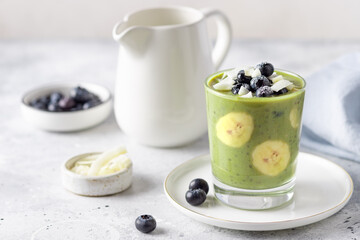 healthy detox chia pudding, topped with blueberries, coconut chips. Vegan breakfast with matcha green tea, banana, chia seeds, almond milk. Gray background.
