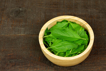 Tulsi or Holy basil leaf in wooden bowl on wooden background. Tulsi is used in ayurvedic medicine.