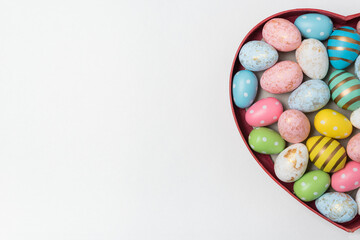 Obraz premium Heart shaped box with Easter eggs on white background. Top view, copy space. Happy easter.