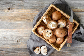 Mushrooms in a basket on the brown wooden kitchen table. Champignons