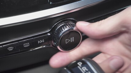 man presses play button and increase volume of multimedia in car. closeup view