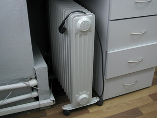 The oil-gray portable heater in the office is turned off under the nightstand.