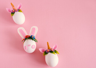 Top view flat lay easter eggs unicorns and rabbit on a pastel pink background. Minimal easter card. Copy space.
