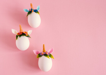 Top view flat lay easter eggs unicorns on a pastel pink background. Minimal easter card. Copy space.