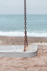 Close up old rusty swing in front of sea at beach 