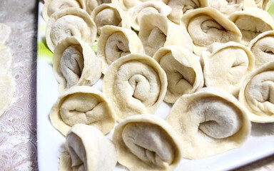 Homemade Russian raw dumplings on the table with flour.