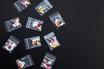 Colorful tablets with capsules and pills in medicine plastic zip lock bags on dark background.
