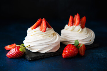 Anna Pavlova cake with cream and fresh strawberries on a dark