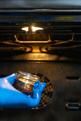 a man in blue gloves took off the shade of a light bulb in the oven to remove grease