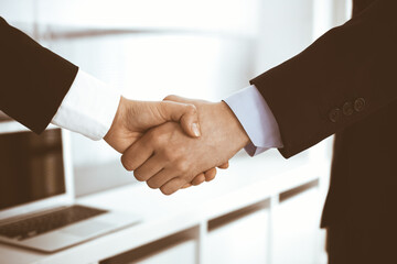 Businessman and woman shaking hands in office. Concept of handshake as success symbol in business