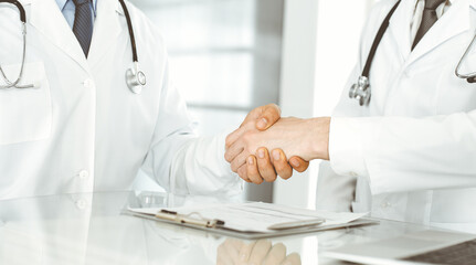 Two doctors are shaking hands as agreement about patient's treatment, close-up. Medical help, medicine concept