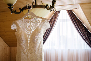 Wedding dress hanging on a chandelier in a hotel room