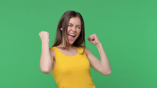 Happy joyful brunette young woman 20s years old in yellow casual tank top posing isolated on green background studio. People lifestyle concept. Count countdown 1 2 3 one two three doing winner gesture