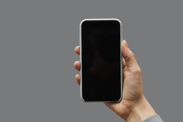 Minimal graphic background of female hand holding smartphone with black screen against gray background, copy space